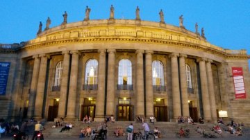 Während in der Oper Stuttgart die Abendvorstellung läuft, lauschen draußen Spaziergänger der Musik durch die geöffenten Fenster (c) Thomas Koch
