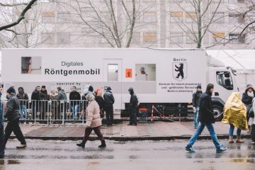 Schlangestehen vor dem Berliner Röntgenmobil bei Minusgraden und schneidendem Wind. Eine Frau versucht, sich mit einer Erste-Hilfe-Decke zu wärmen. (c) Julia Nimke